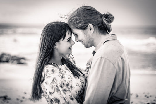 a man and woman standing next to each other on a beach