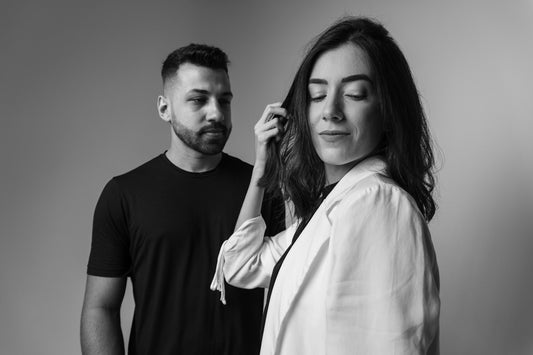 a man standing next to a woman who is brushing her hair