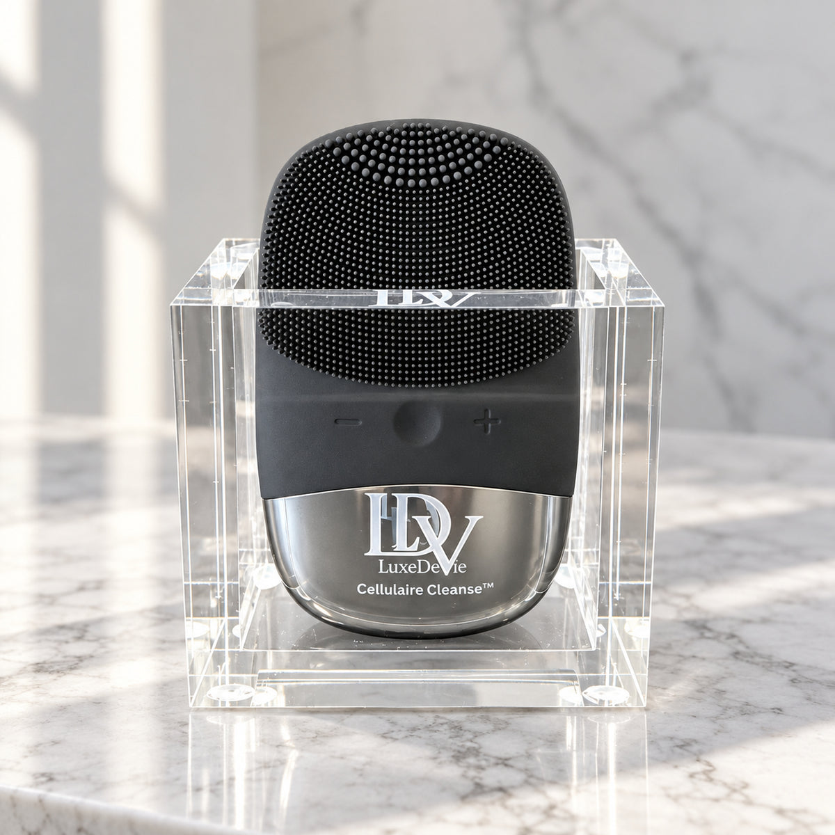 Black Cellulaire Cleanse Signature device seated in its engraved clear acrylic LDV Signature Cradle on a white marble vanity.
